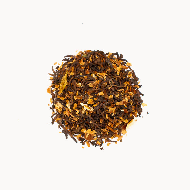 A pile of vintage Rishi Tea & Botanicals Orange Blossom Pu'er tea on a white background.