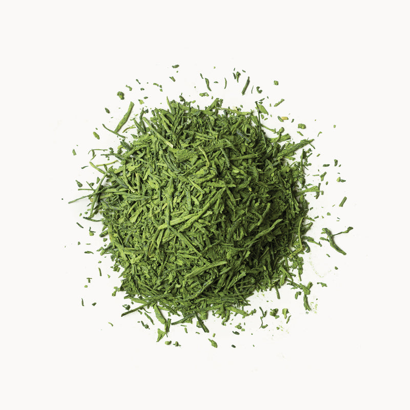 A pile of Matcha Super Green leaves on a white background, by Rishi Tea & Botanicals.